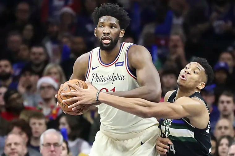 Joel Embiid gets the rebound as Giannis Antetokounmpo reaches over in the third quarter of a game at the Wells Fargo Center on Wednesday.