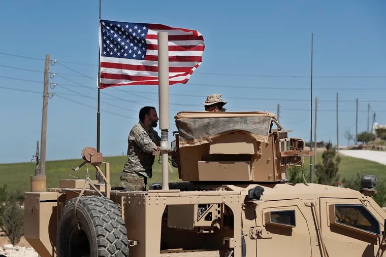 In this April 4, 2018 photo, a U.S-backed Syrian Manbij Military Council soldier (left) speaks with a U.S. soldier  at a U.S. position near the tense front line with Turkish-backed fighters, in Manbij town, north Syria.