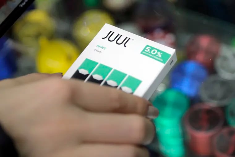 A woman buys refills for her Juul at a smoke shop in New York. The e-cigarette maker Juul Labs said Thursday that it will halt sales of its best-selling mint-flavored vaping pods.