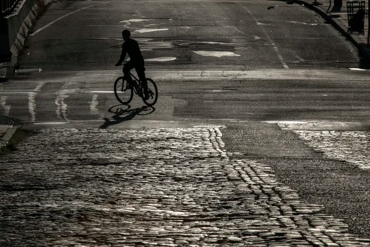 On a chilly Tuesday morning, a biker and his vehicle cast a shadow at Front and Chestnut Streets.