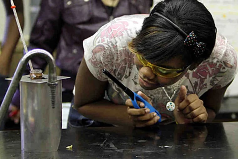 Mjaan McIvor, 15, a Central High School biology student, checks on the progress of an experiment in which the caloric content of a typical school lunch was determined by burning ingredients. (Laurence Kesterson/Staff)
