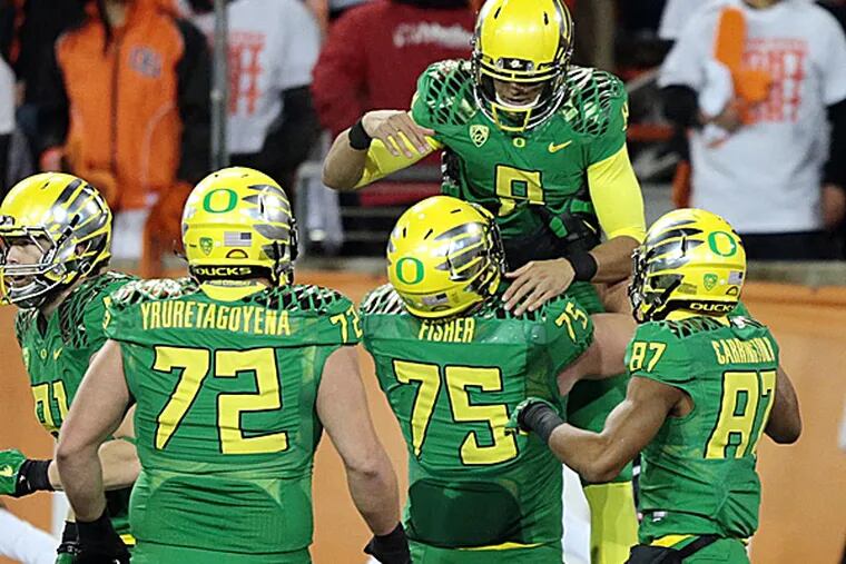 Oregon quarterback Marcus Mariota is congratulated by teammates after a touchdown. (Scott Olmos/USA Today Sports)