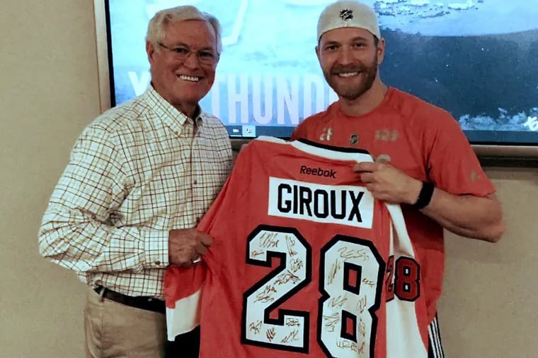 Former NFL coach Dick Vermeil (left) poses with Flyers captain Claude Giroux. At Giroux’s request, Vermeil gave the Flyers an inspirational speech  Tuesday.