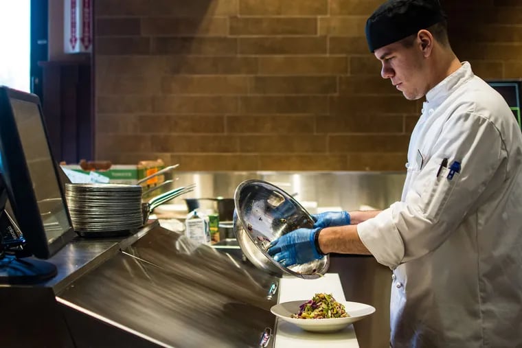 Chef Justin Fritz prepares an Italian chopped salad in the Pub, a restaurant and bar at Wegmans in Glen Mills. The store is set to open Sunday.