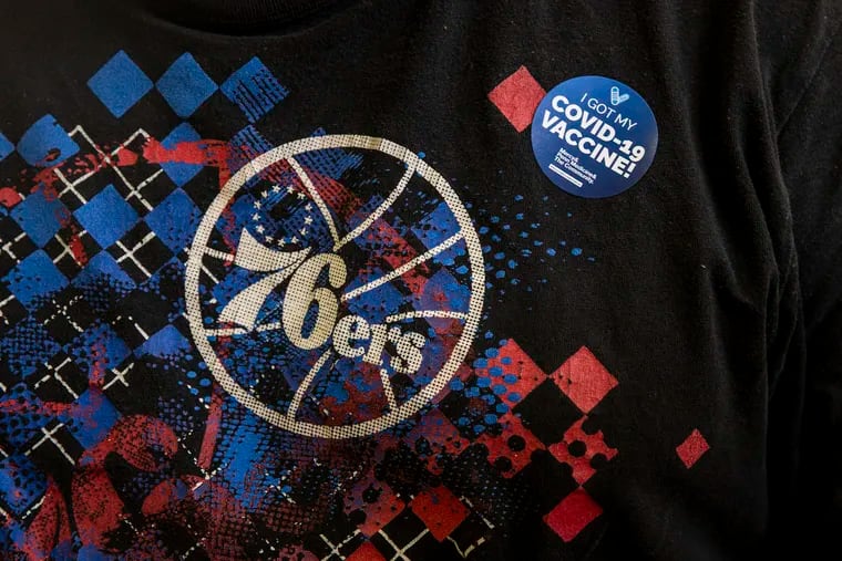 A man wearing a 76ers shirt received a sticker after getting his COVID-19 vaccination at the Preparatory Charter School in South Philadelphia on April 10.