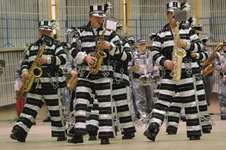 Jailhouse flock: Wearing prison garb, Greater Kensington band members prepare for New Year&#0039;s. The band&#0039;s feathery finery comes courtesy of Mummer brethren who helped out after a fire.