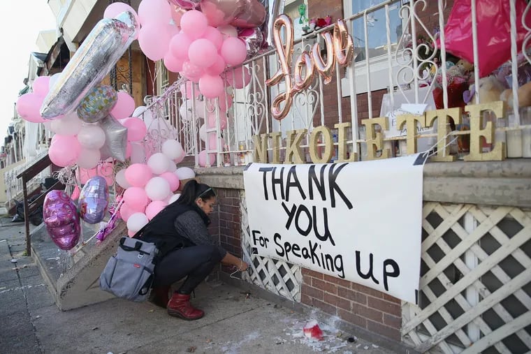 Rosalind Pichardo, founder of Operation Save Our City, an organization that supports families of murder victims, puts up a sign in front of the home where two-year-old Nikolette Rivera was shot and killed Sunday in Philadelphia's Kensington section