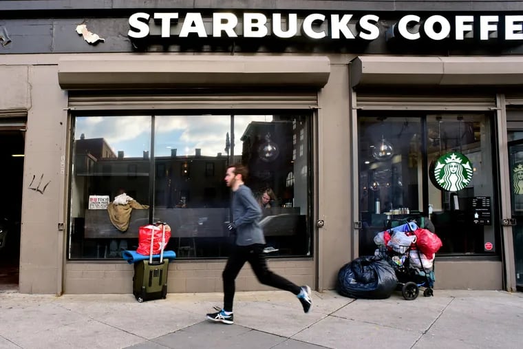 Plastic bags, a shopping cart and suitcase are parked outside the Starbucks at Broad and Pine Streets, March 4, 2019. Inside, a recent redesign left only two high-top tables in a corner, a half-dozen tall stools along the windows, and an expanse of vacant territory.