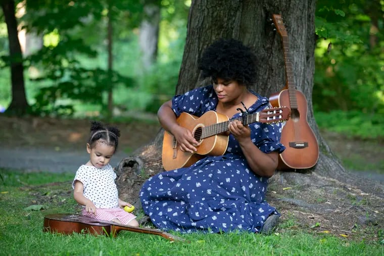 Painted Bride's Resistance Gardens project, a program exploring food politics and our relationship with nature in partnership with local artists, gardens, farms and foragers. Philly Forests director Jasmine Thompson, right, plays guitars with Leone Green-Love, 2, at their potluck dinner at Awbury Arboretum.