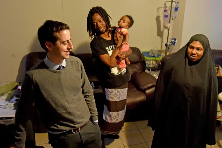 Curtis Sampson (center, holding 10 month old daughter Honesty) and Gerrell Martin talk with their attorney Dan Urevick-Ackelsberg (left) at their home March 16, 2017.