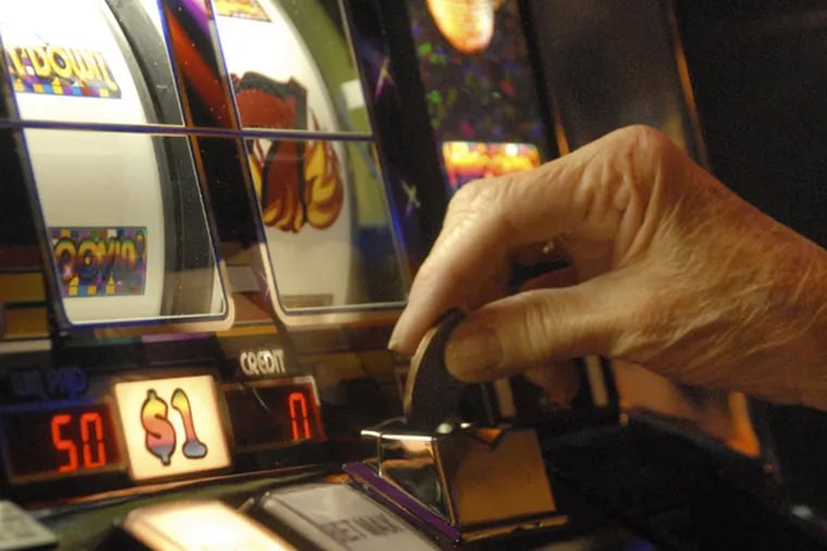 A player puts a dollar coin in a slot machine. (AP Photo/Curt Hudson)