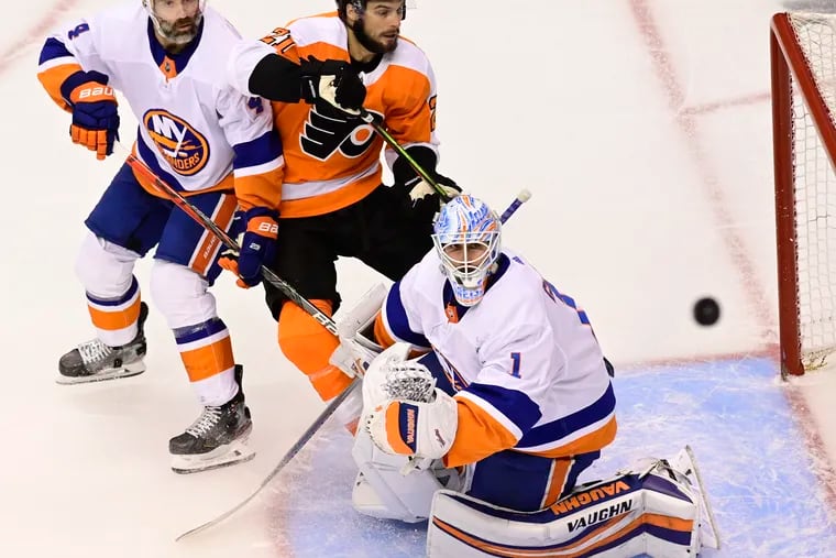 A shot goes over the net as Islanders goaltender Thomas Greiss, Islanders defenseman Andy Greene (left), and Flyers center Scott Laughton looks on in the second period.