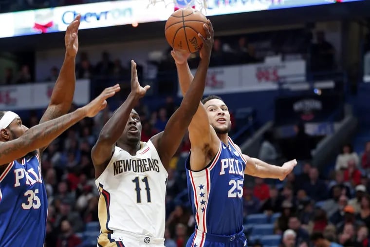 Pelicans guard Jrue Holiday (11) goes to the basket between 76ers guard Ben Simmons (25) and forward Trevor Booker in the first half.