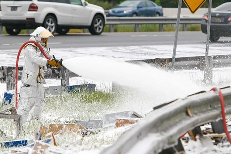 Dominic Pizzo with Station 33 Delaware Air Guard sprays foam on millions of bees along I-95 near Newark, Del.,  Wednesday, May 21, 2014. The ramp to I-95 in Newark reopened more than 12 hours after the rig carrying an estimated 16 million to 20 million bees crashed Tuesday. Crews were spraying foam to contain the swarms.  (AP Photo/The Wilmington News-Journal, Suchat Pederson)