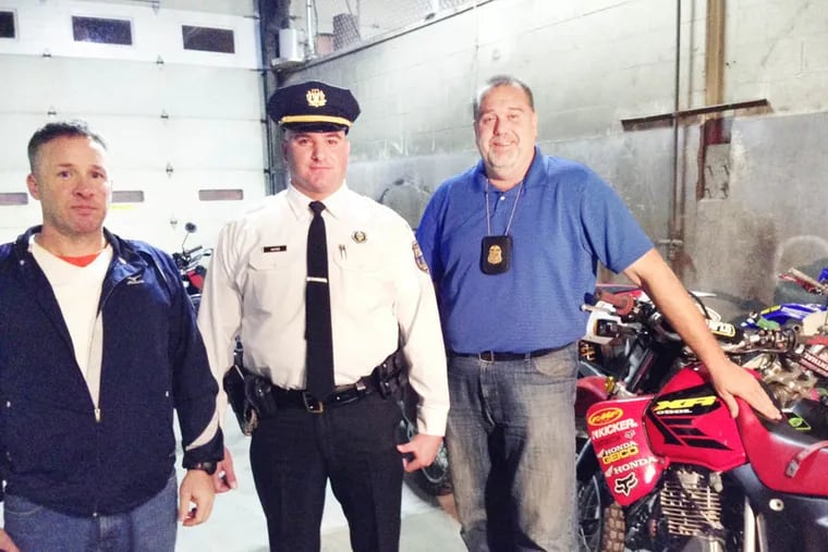 Chief Inspector Dennis Wilson, left, 24th District Lt. Marc Hayes and Major Crimes Det. Jack Logan, right, wait for another tow truck to bring more ATVs and dirt bikes seized on the streets of Philadelphia during a citywide sting Sunday. (Morgan Zalot / Daily News Staff)