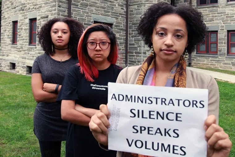 Allegra Massaro, right, holds one of the many signs she printed in response to the administration's silence on the confederate flag controversy that enveloped Bryn Mawr College. Fellow students Olivai Porte, left, and Michelle Lee stand with Massaro in front of Radnor Hall, where the incident occurred. ( MICHAEL BRYANT / Staff Photographer )