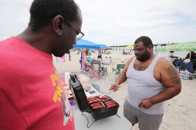 Steven Wesley(right) grills hotdogs and sausage on the Caspian Avenue beach in Atlantic City, N.J. on Sunday, Aug. 14, 2022.