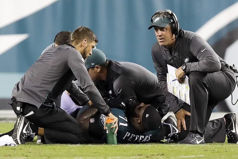 Eagles head coach Doug Pederson kneels next to injured offensive tackle Jason Peters during a game against Washington.