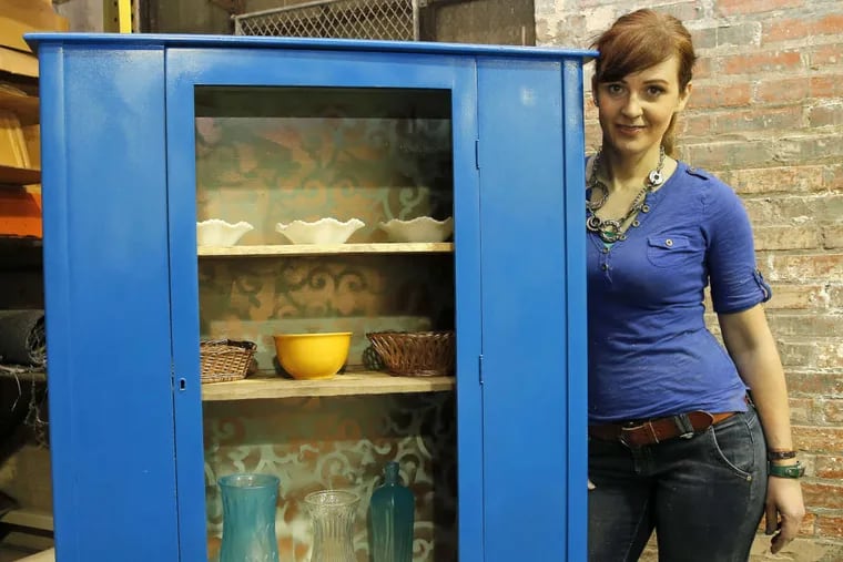 Theresa Clement with the restored cabinet. It, along with other ReStore-made pieces, will be offered at auction at the store from Jan. 25 to Feb. 1.