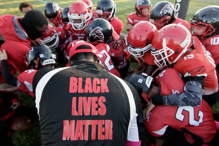 Wearing a team shirt with BLACK LIVES MATTER on the back, Gibbstown sophomore football team coach Rashad Thomas, and the rest of the team, say a prayer before their game against Pennsville at the Gibbstown Youth Football Field in Gibbstown, N.J. on Oct. 17, 2020.
