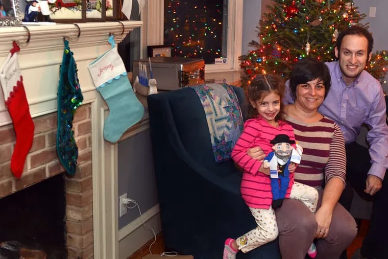 Josie Schwartz, 4-1/2, holds the family's Mensch, posing with her mother and father, Jon and Courtney Schwartz, in their Haddonfield living room.