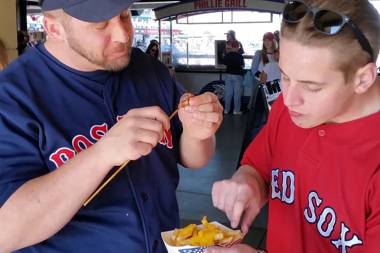 Matt, left, and Alex Caton, brothers, take a food break at the Lehigh Valley IronPigs baseball game. DAN MEYERS / For The Inquirer