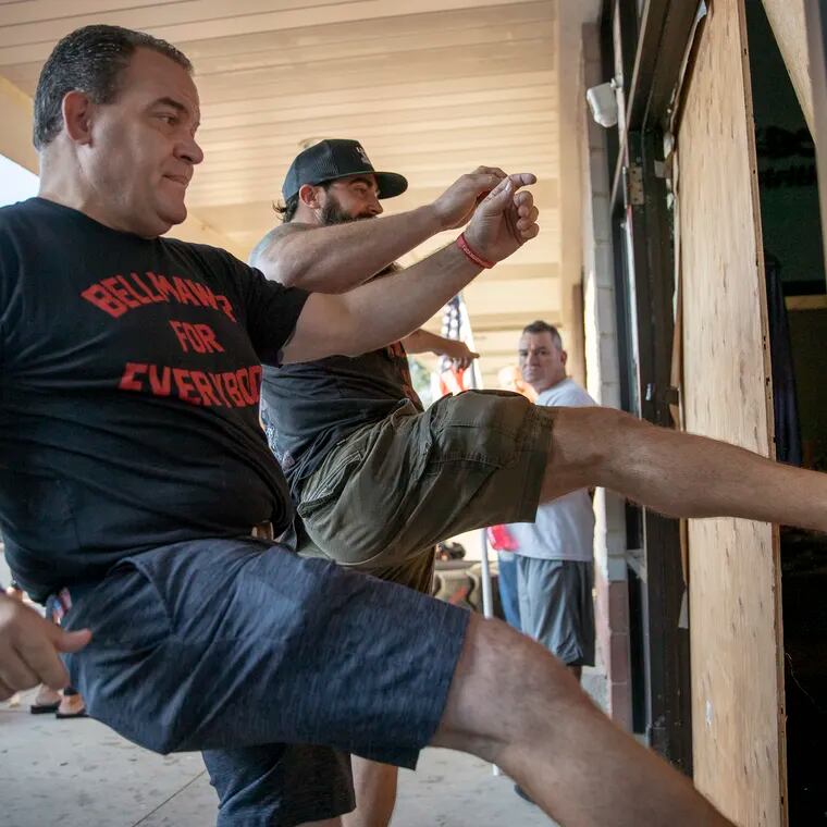 File photo of Atilis Gym owners Frank Trumbetti (left) and Ian Smith kicking down wooden boards covering the entrance to the facility in Bellmawr, N.J., on Aug. 1, 2020.