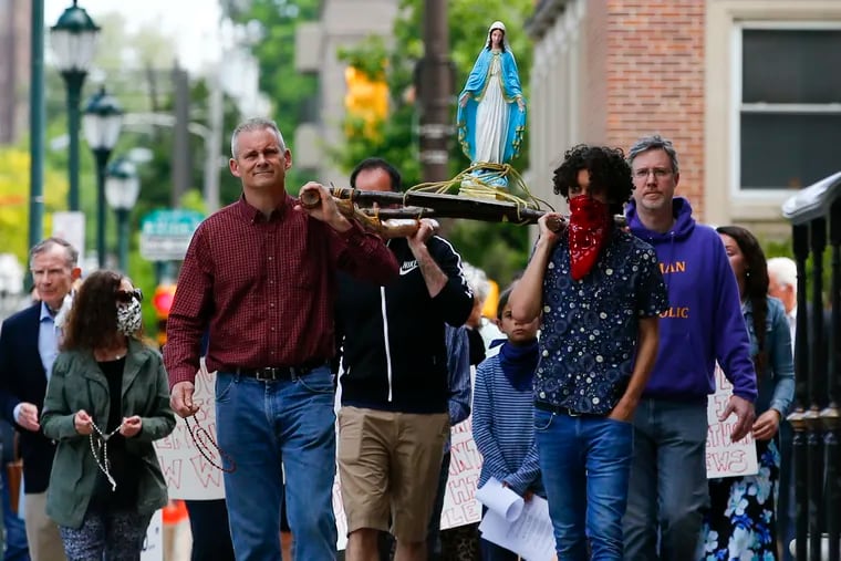 Parishioners carry the statue of the Virgin Mary near the Cathedral Basilica of SS. Peter and Paul, along the Benjamin Franklin Parkway before an outdoor Mass at the Sister Cities Park on Sunday, calling on Archbishop Nelson Pérez to restore public Masses.