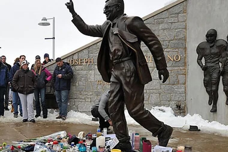 Fans left flowers and memorabilia next to the Joe Paterno statue outside Beaver Stadium on Sunday. (Nabil K. Mark/For the Inquirer)