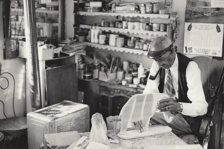 Elijah Pierce working on a large-scale sculpture of an elephant in his barber shop studio, Columbus, Ohio, circa 1970.