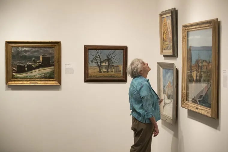 A visitor examines an exhibit of local school districts’ art collections at the James A. Michener Museum. The exhibit includes 15 paintings from the Philadelphia School District.