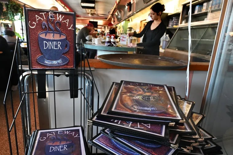 Hailey Olmeda, a server at the Gateway Diner for more than a year, works behind the counter and a stack of menus during breakfast service Sunday, the diner's final day of operation after more than 32 years. The owners announced the news on Facebook on Friday, citing "the Westville Route 47 Bridge project and eminent domain."