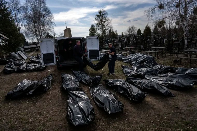 Cemetery workers unload bodies of civilians killed in Bucha, on the outskirts of Kyiv, Ukraine, on Thursday.