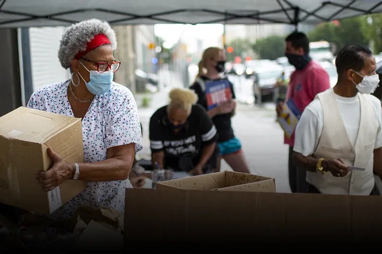 Carmen Lassus, volunteer at The Center for Returning Citizens Community Healing Center, helps hand out food to people in the community along Broad Street in North Philadelphia on Friday, July, 31, 2020.