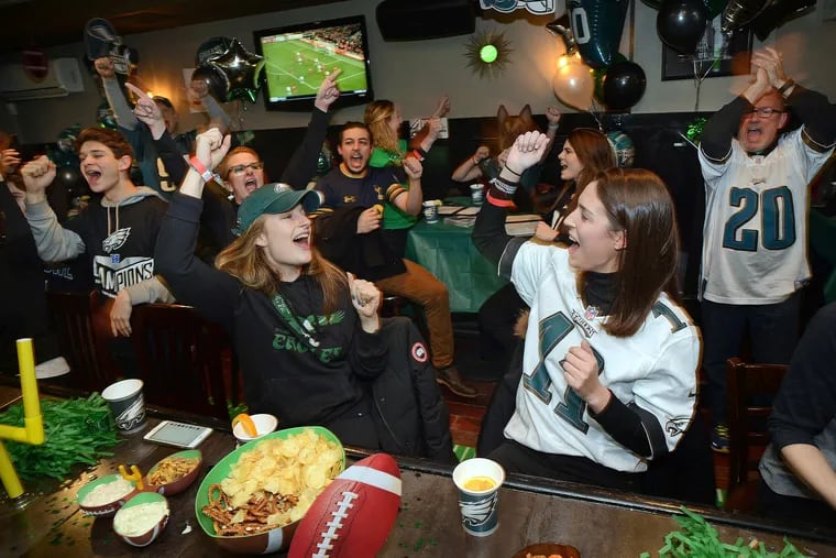 Philadelphia Eagles fans Emily Sax (with cap) of New York and Taylor Durovsik #11 of Philadelphia sing the Eagles fight song at Smith's Bar & Restaurant in 2018 in Philadelphia.