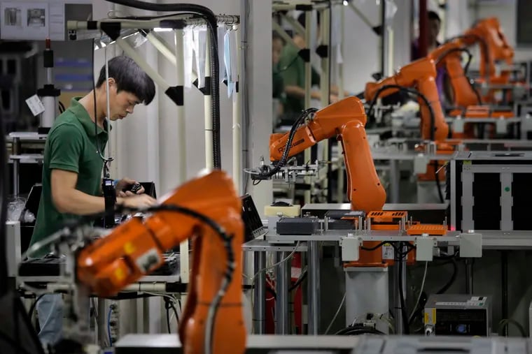 A man works amid orange robot arms at technology factory. Graham Partners, which recently raised $645 million, invests primarily in companies that work in the manufacturing space.