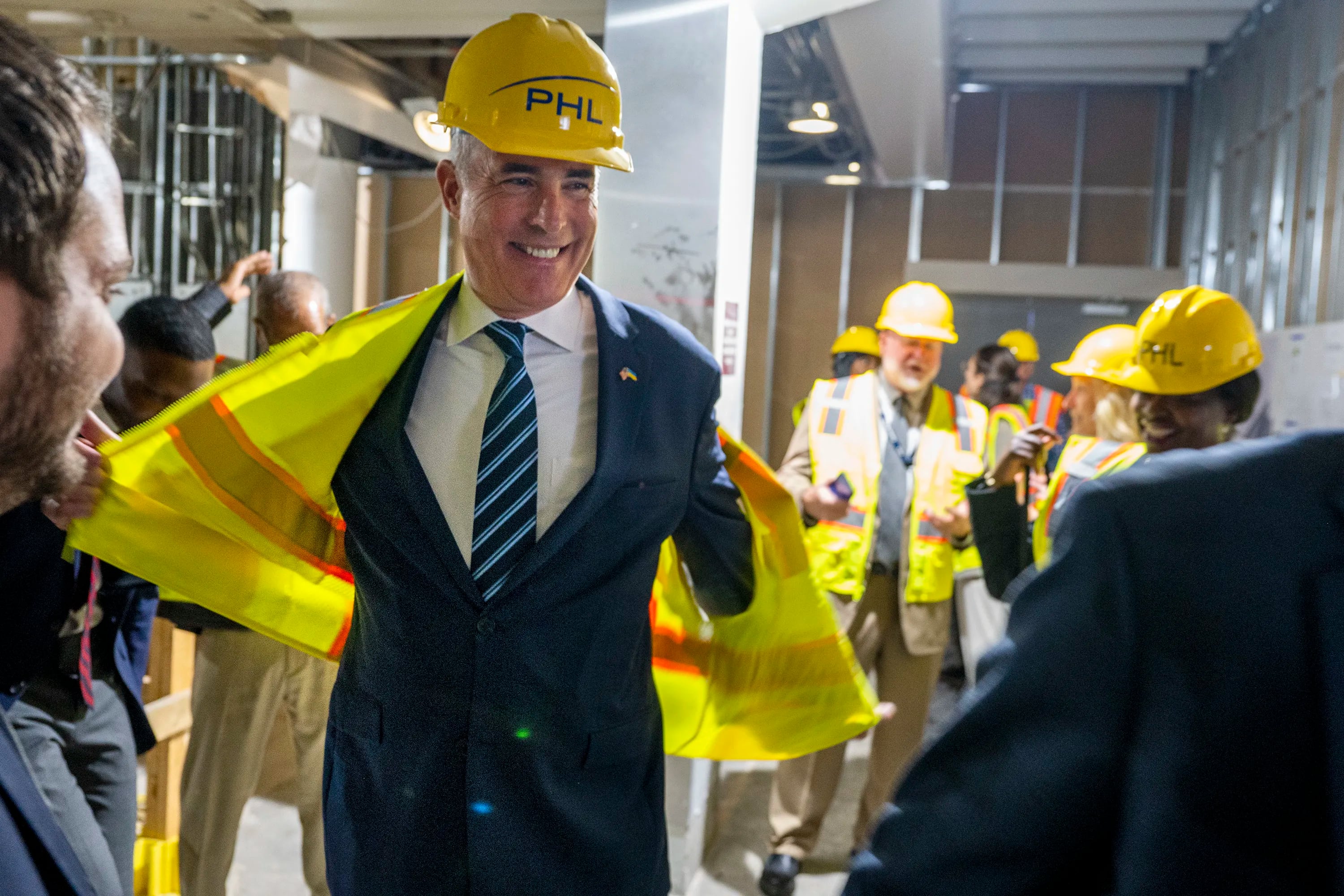 Sen. Bob Casey takes off his safety-wear after he and other elected officials and airport workers viewed construction on another new restroom at Philadelphia International Airport . 