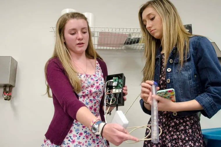 Kate Pelcin (left) and Kristina Griste work on the Aqua Tweeter, a flood-detection device they helped develop at Downingtown High School West.
