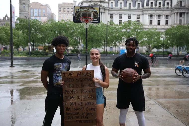 Khalil Gardener (left), Stephania Ergemlidze, and Jaquill Shackelford are trying to ease Center City tension by wheeling her basketball standard to various locations and inviting people to play. It has been used by police and protesters alike.