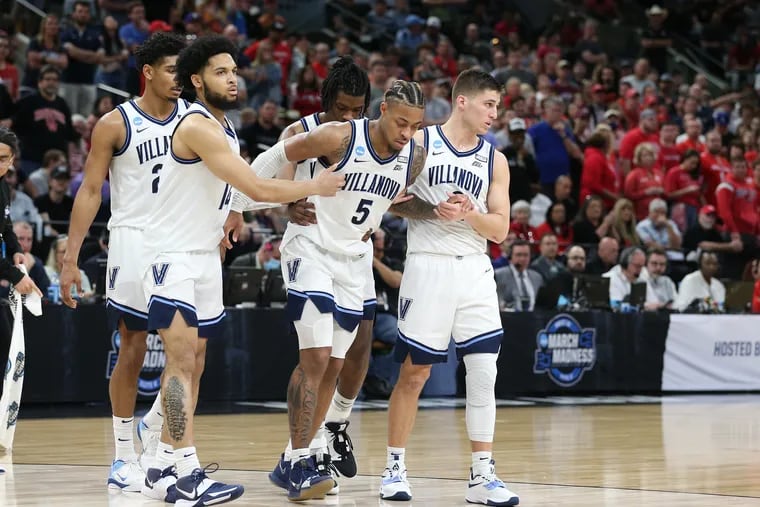 Justin Moore, center, of Villanova is helped off the court.