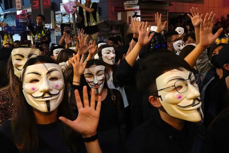 People in Guy Fawkes masks raise their hands as they gather on a street in Hong Kong, Thursday, Oct. 31, 2019.