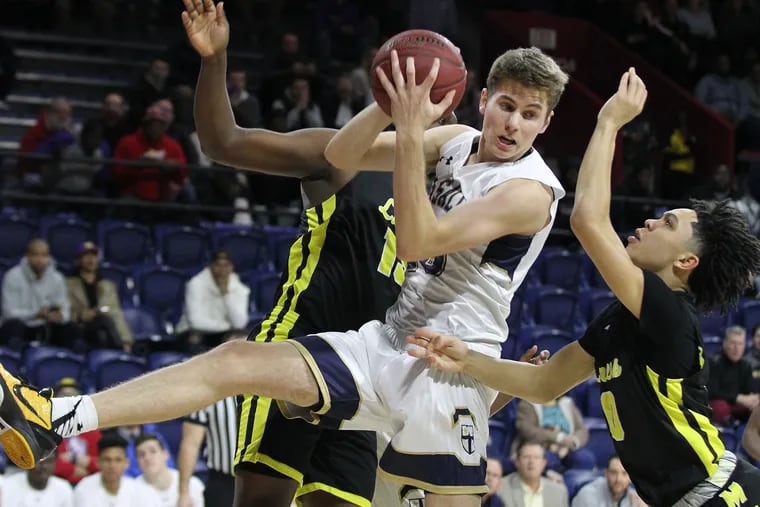 Konrad Kiszka, center, of La Salle pulls down a rebound between Jamil Manigo, left, and Glenn Smith, right of Bishop McDevitt in the 1st quarter of the Catholic League semifinals at the Palestra on Feb. 21, 2019.