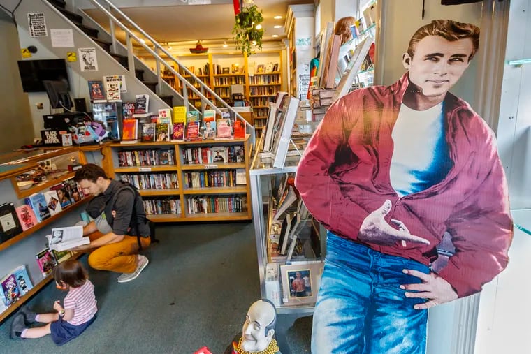 A cardboard cutout of James Dean stands at the front door of Giovanni's Room, as Matthew Shelton and Nora Shelton look over the books at the checkout counter.