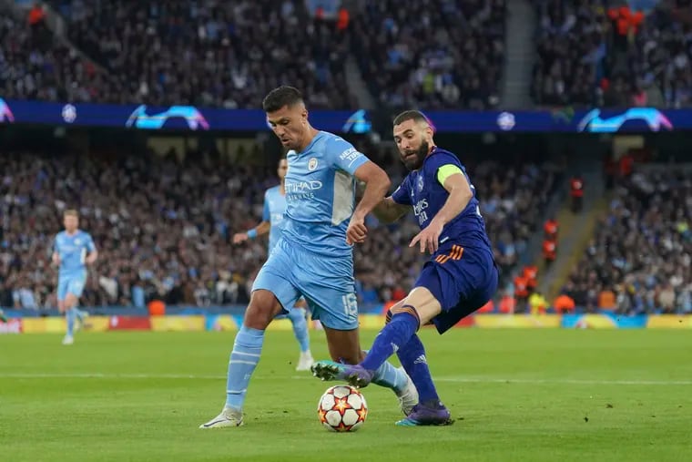 Real Madrid's Karim Benzema (right) battling for the ball with Manchester City's Rodrigo during the first game of their Champions League semifinal series, last Tuesday in Manchester, England.