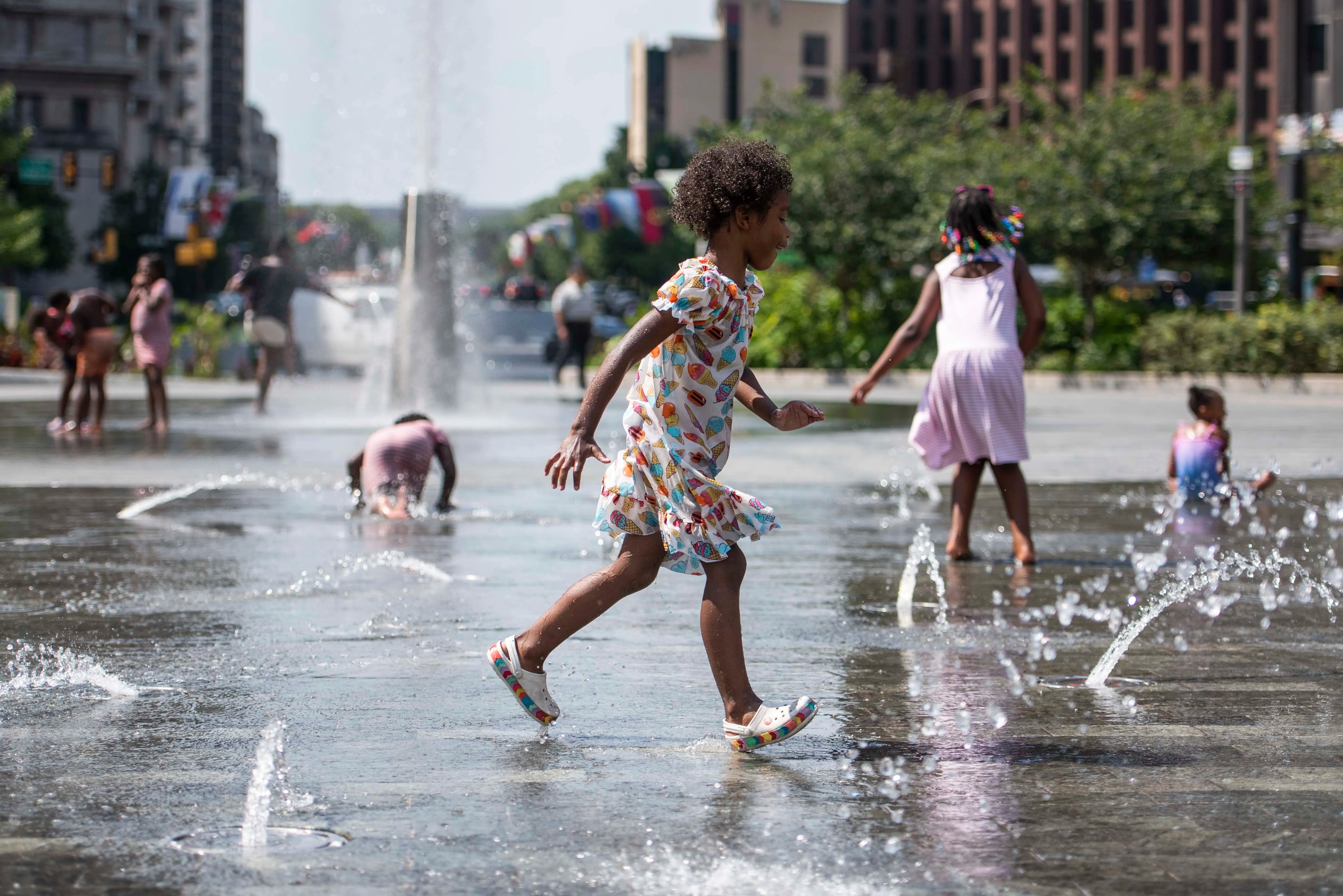 A child runs across the splash pad at Love Park on Friday, July 28, 2023. A heat wave hit the Philadelphia region on Friday, with temperatures reaching nearly 100 degrees.
