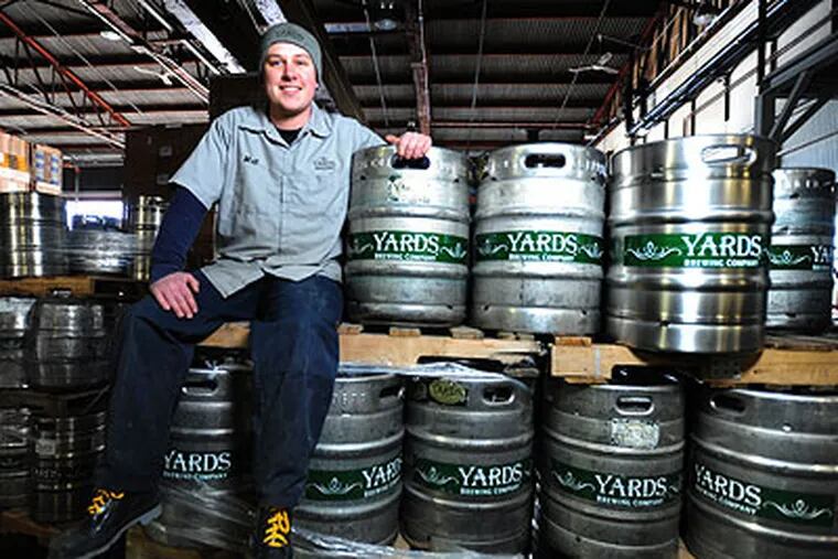 Matt Hall, 25, the "cellar man" at Yards Brewing Company, assisting the brewers and monitoring the beer during fermentation process, sits amid some kegs of Yards brew. (Clem Murray / Staff Photographer)