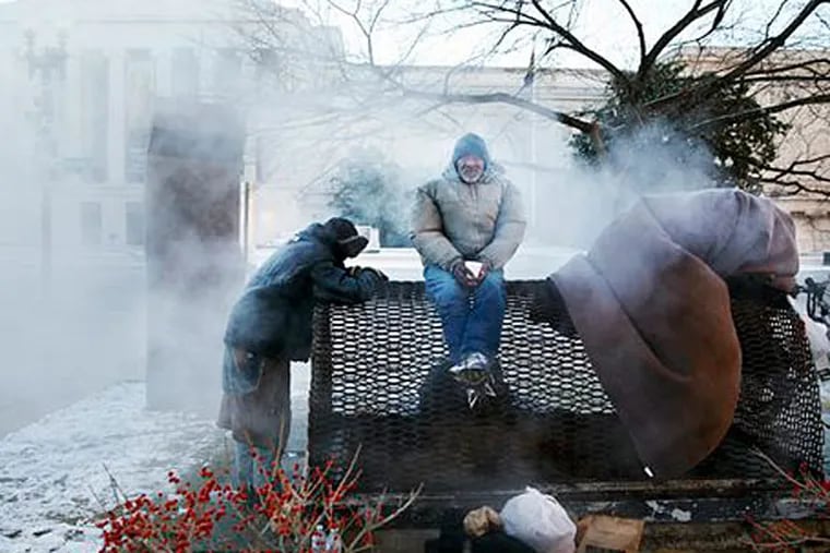 Four homeless men warm themselves on a steam grate by the Federal Trade Commission, blocks from the Capitol, during frigid temperatures in Washington, Saturday, January 4, 2014. A winter storm that swept across the Midwest this week blew through the Northeast on Friday, leaving bone-chilling cold in its wake. (AP Photo/Jacquelyn Martin)