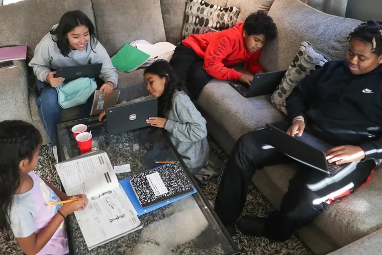 From left, Essence Roberts, 6, Dulce Serrano, 16, Jade Roberts, 9, Nathan Roberts, 12, and Lamar Jr. Roberts, 15, do their homework together at home in Yeadon, Pa. on Thursday, Oct. 20, 2022. LaMar Roberts and the 5 children have been separated from his wife and mother, Karen Roberts, for about 18 months.