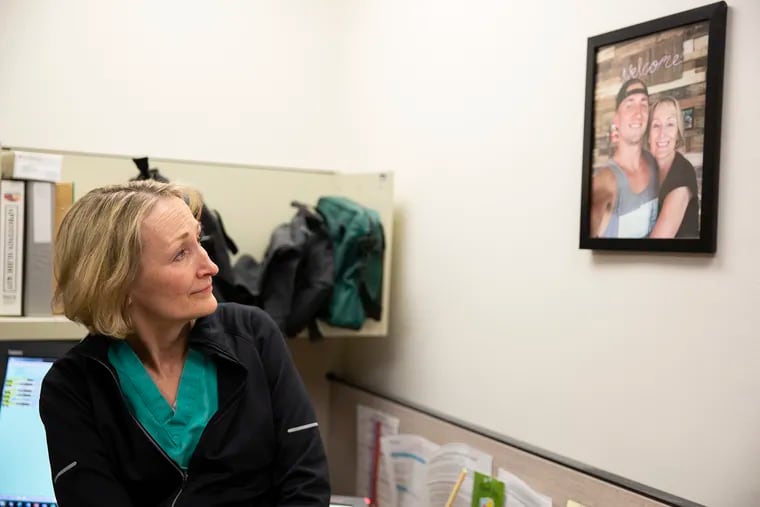 Dr. Bonnie Milas looks up at a photo of her son, Robert, who died of an overdose, in her office at the Hospital of the University of Pennsylvania. Milas, an anesthesiologist at Penn, has become an advocate for overdose prevention.