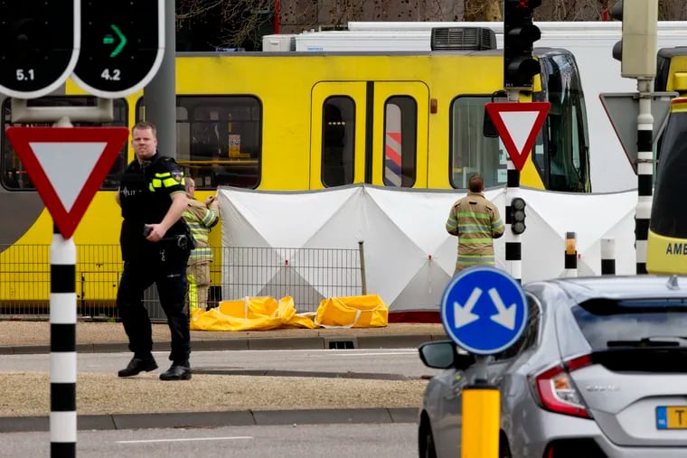 Rescue workers install a screen on the spot where a body was covered with a white blanket after a shooting in Utrecht, Netherlands, on Monday.